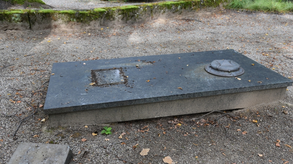 Ein umgetretener Grabstein auf dem Friedhof, der neben der Grabstelle liegt.