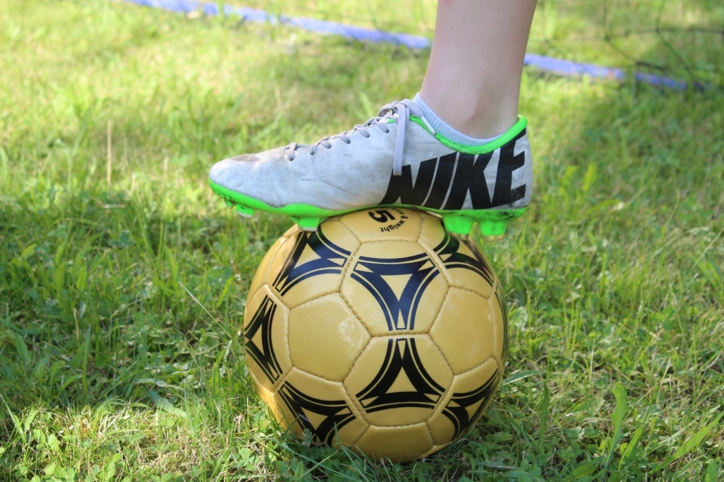 Fußball mit Fußballschuh auf grünem Rasen (Symbolbild)